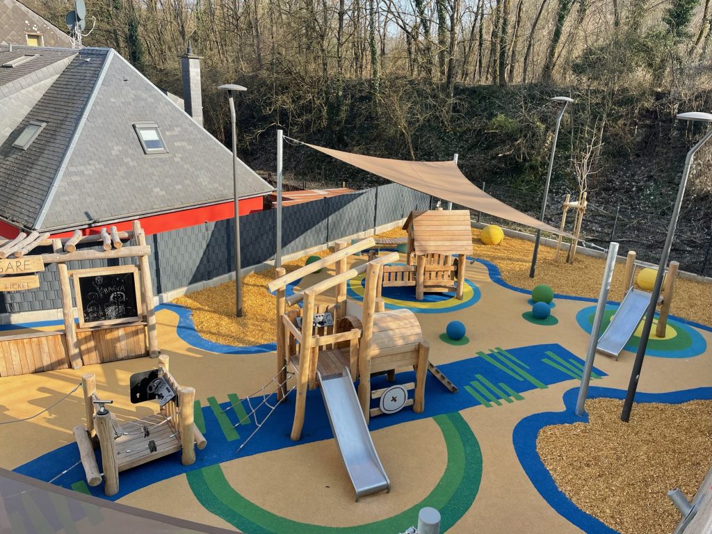 Voiles d'ombrage abritant une aire de jeu en robinier dans une école.
