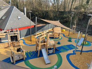 Voiles d'ombrage abritant une aire de jeu en robinier dans une école.