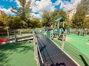 ire de jeux en plein air avec structures en matériaux recyclés, intégrée dans un environnement urbain et verdoyant