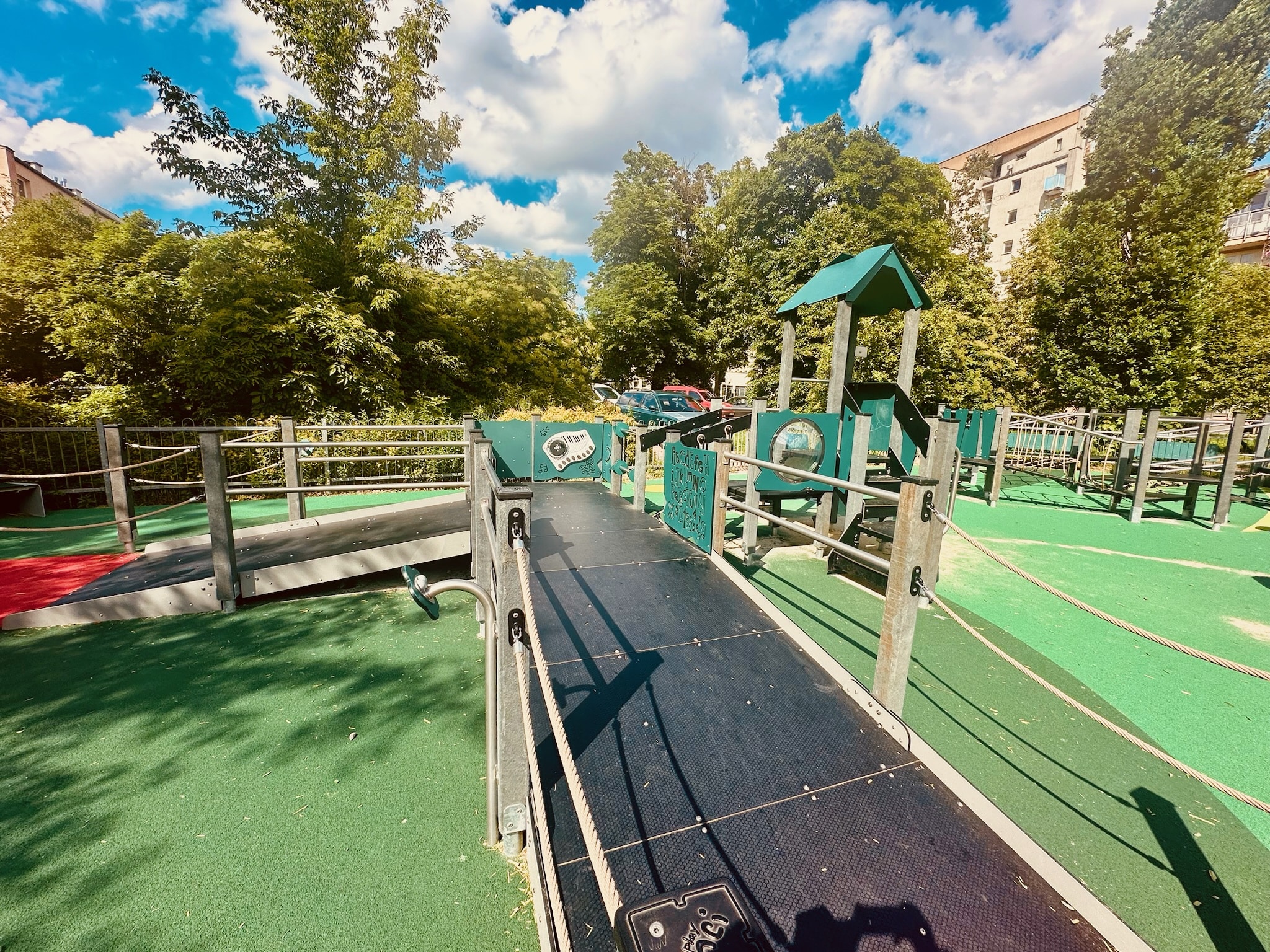 ire de jeux en plein air avec structures en matériaux recyclés, intégrée dans un environnement urbain et verdoyant