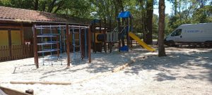 Grande structure de jeux en bois avec échelle, filet d'escalade et mur d'escalade.
